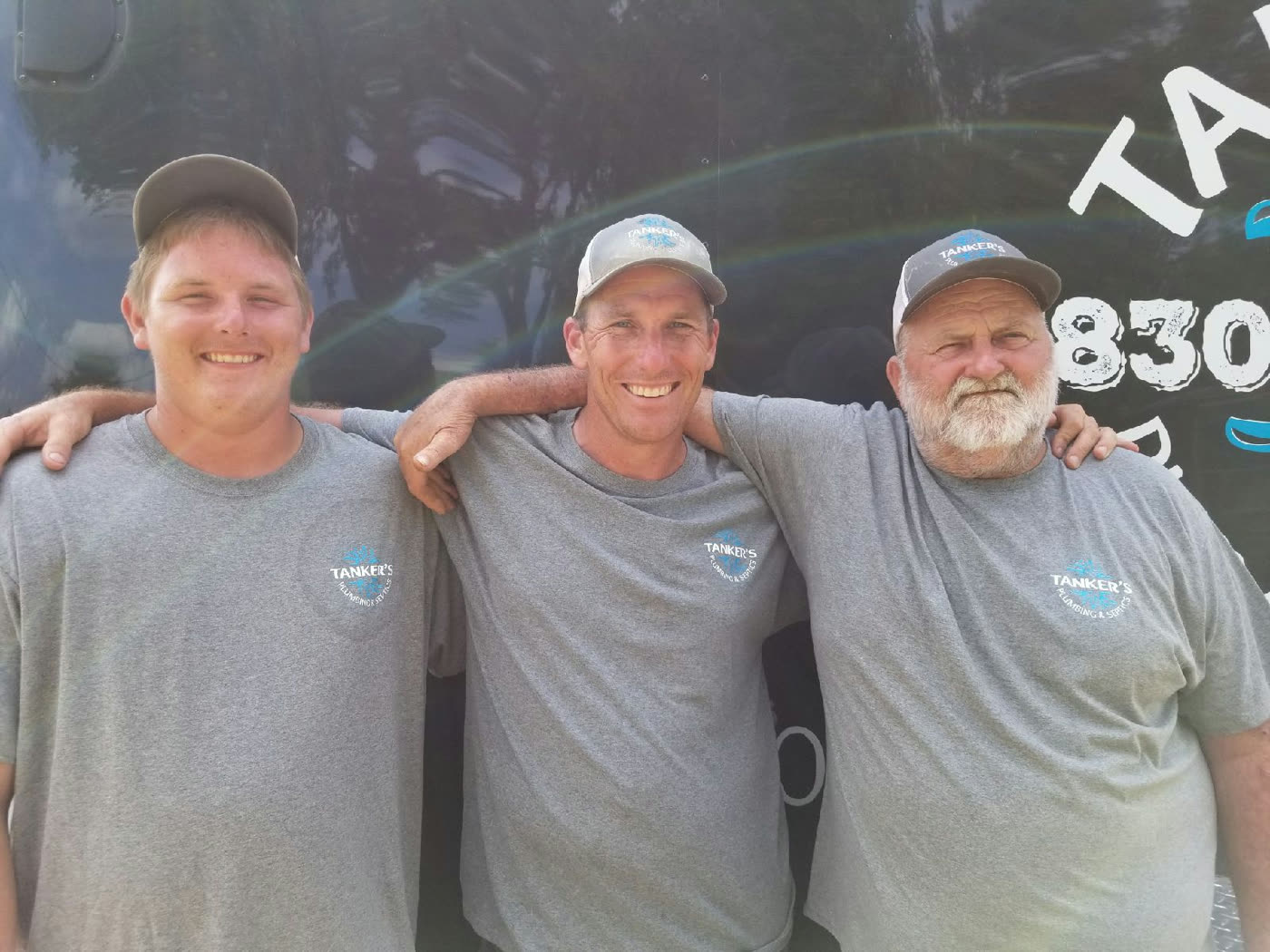 Three generations of Harris men together in front of a Tanker's Plumbing service vehicle